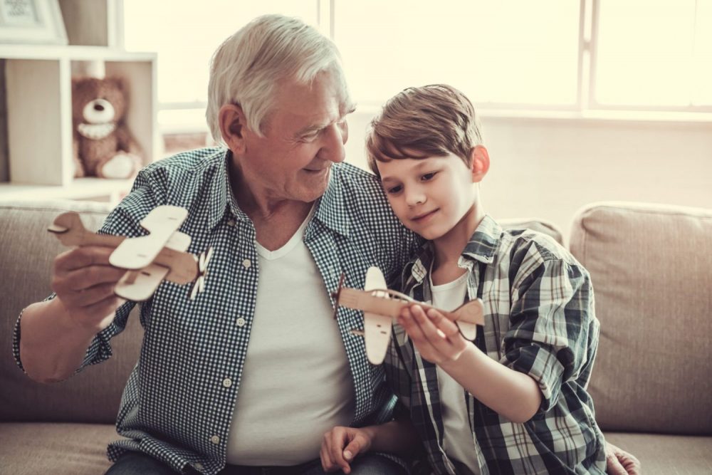 A grandfather playing with airplanes with his grandson.